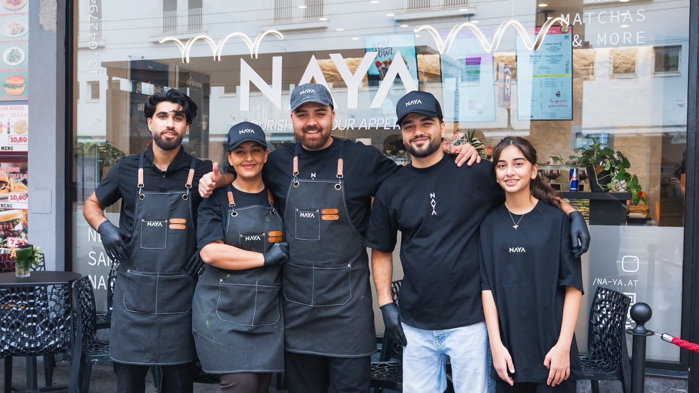 Das Team von NAYA in Schürzen und Kappen mit Logo vor dem Lokal